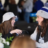 2 women looking at each other with picture in hand on phone